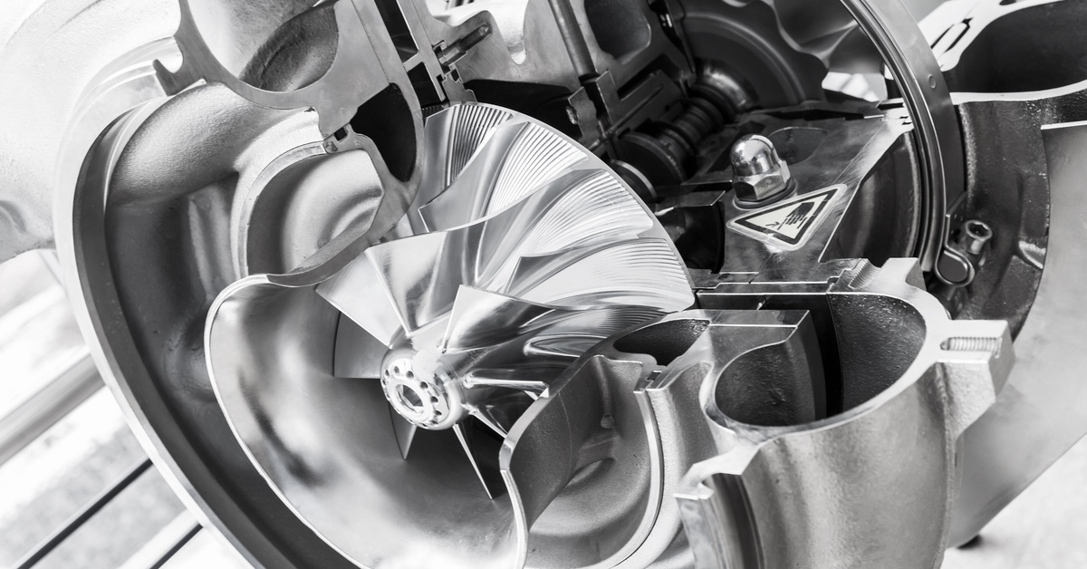 A piece of a car’s turbocharger. The turbocharger has a cross-section taken out of it, exposing internal mechanisms.