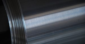 The side of a metal tube is reflecting a light source from just off camera. The metal is a bluish gray.