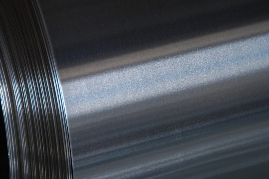 The side of a metal tube is reflecting a light source from just off camera. The metal is a bluish gray.