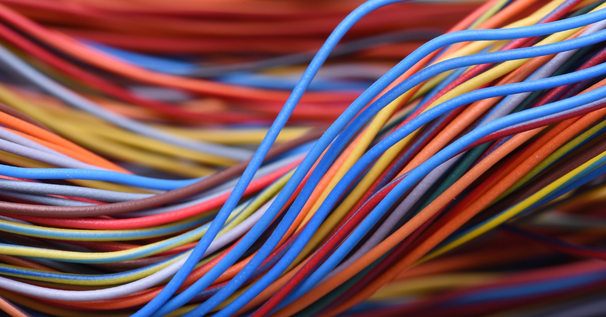 A closeup of cables and wires in a computer network system. The wires are red, blue, and yellow.