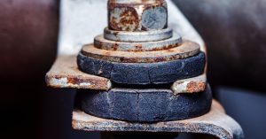 A rusted nut is attached to a bolt. There is a rubber ring around the metal components.