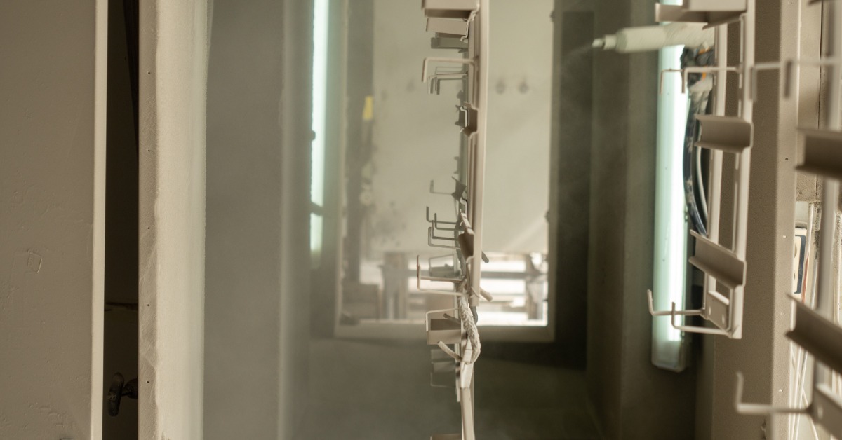 Pieces of metal are hanging from a ceiling. They are being sprayed by some industrial coating.